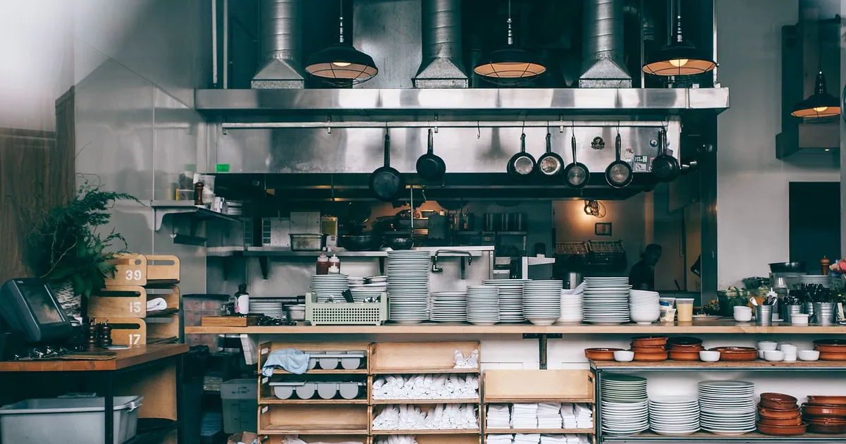 Cluttered open-kitchen restaurant with stacked plates and boxes